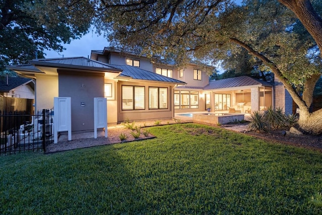 rear view of house with fence, a standing seam roof, a patio, a lawn, and metal roof