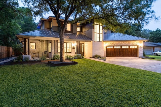 view of front facade featuring a front yard, a standing seam roof, metal roof, an attached garage, and driveway