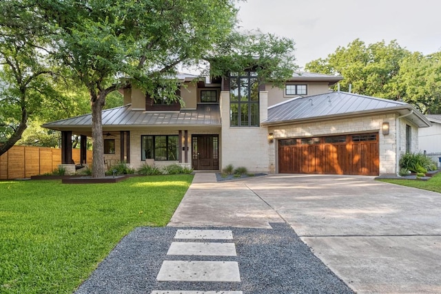 prairie-style home featuring fence, a front yard, a standing seam roof, metal roof, and driveway