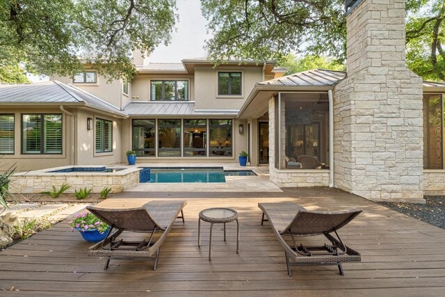 back of property featuring an in ground hot tub, a standing seam roof, a wooden deck, and metal roof