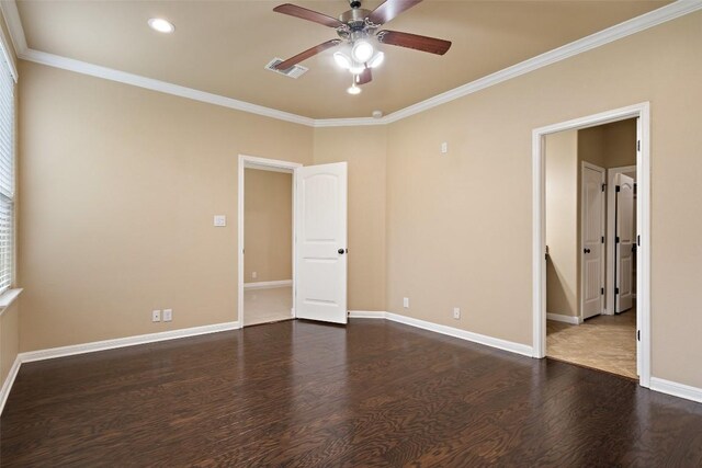 spare room featuring crown molding, dark wood-style flooring, ceiling fan, baseboards, and visible vents