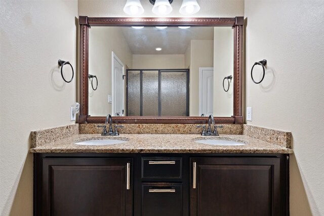 full bathroom featuring a sink, a stall shower, and double vanity