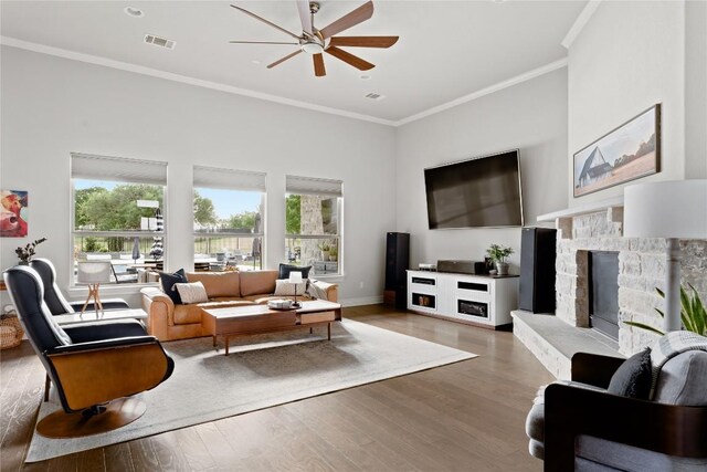 living room featuring visible vents, crown molding, ceiling fan, and a wealth of natural light