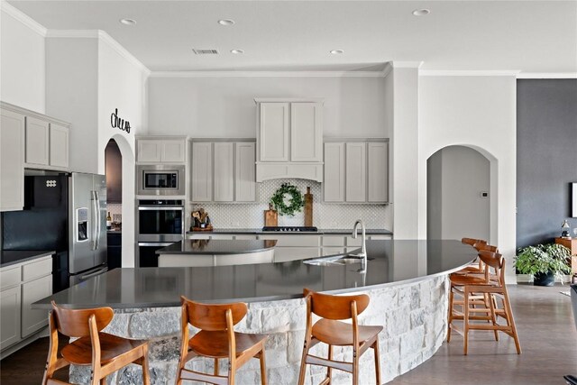 kitchen with arched walkways, decorative backsplash, stainless steel appliances, and a spacious island