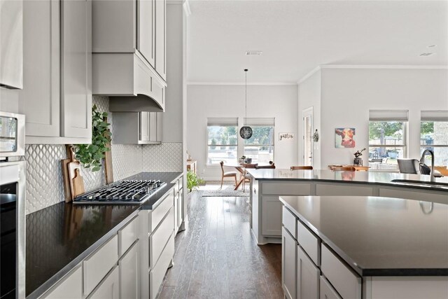 kitchen featuring dark countertops, a sink, gray cabinets, dark wood-type flooring, and ornamental molding