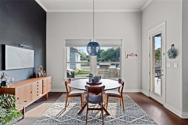 dining room with baseboards, ornamental molding, and wood finished floors