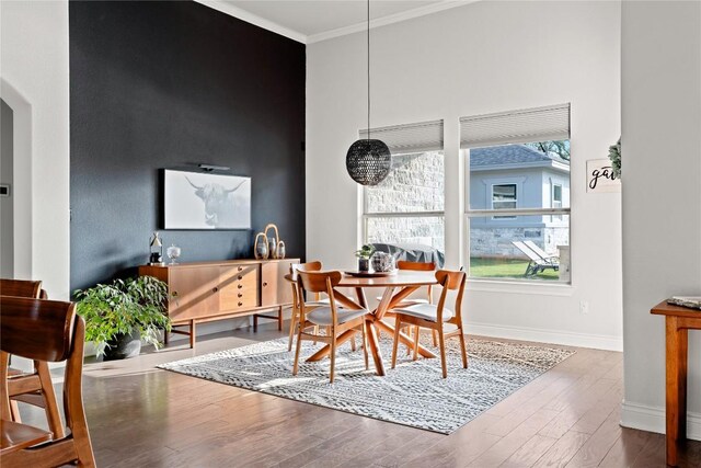dining room with arched walkways, baseboards, ornamental molding, and wood finished floors
