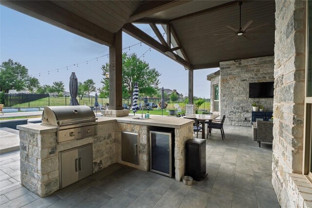 view of patio with fence, ceiling fan, area for grilling, and a bar