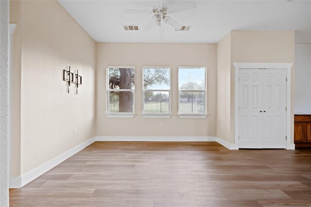 empty room with visible vents, a ceiling fan, baseboards, and wood finished floors