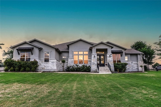 view of front of property featuring french doors, stucco siding, stone siding, and a front yard