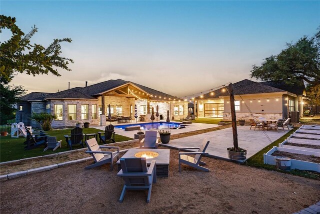 view of property's community featuring a swimming pool, an outdoor fire pit, and a patio area