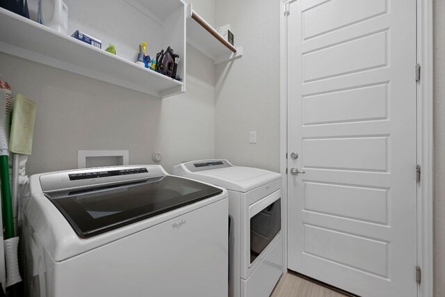 clothes washing area featuring independent washer and dryer, laundry area, and light wood-style flooring