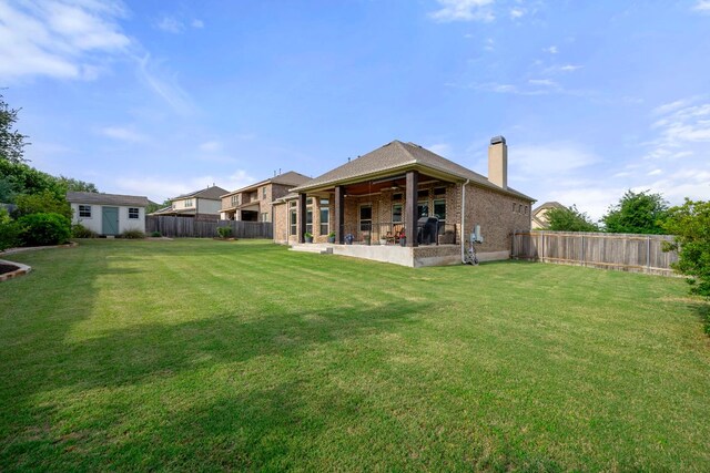rear view of property featuring a fenced backyard, a chimney, a patio area, a lawn, and a ceiling fan