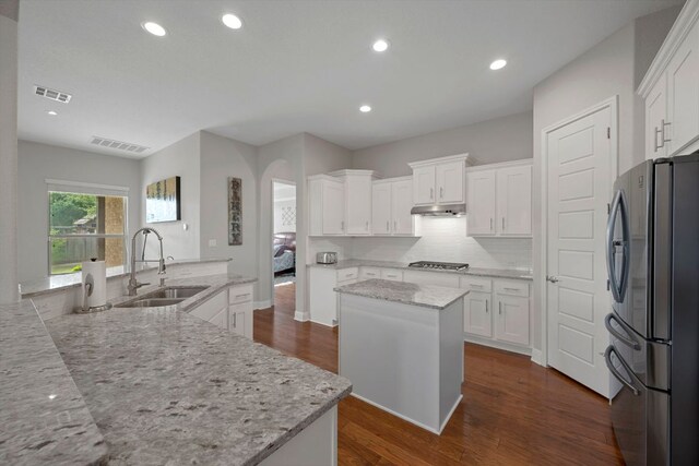 kitchen with stainless steel appliances, visible vents, a large island with sink, and a sink
