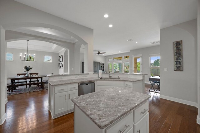 kitchen featuring dark wood-style floors, a center island, a sink, ceiling fan with notable chandelier, and dishwasher