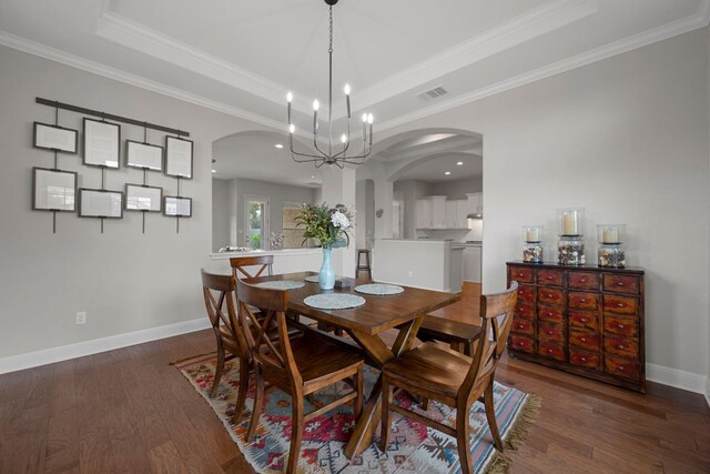 dining space featuring arched walkways, a tray ceiling, hardwood / wood-style floors, and visible vents