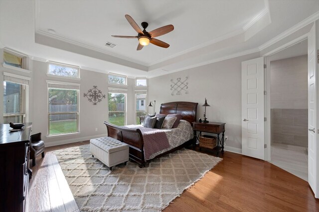 bedroom featuring crown molding, wood finished floors, a tray ceiling, and visible vents