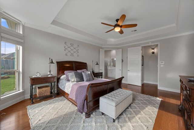 bedroom with baseboards, ornamental molding, wood finished floors, and a raised ceiling