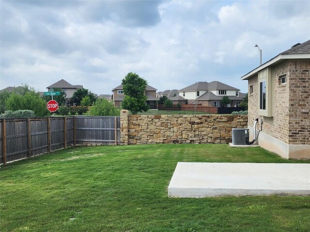 view of yard with fence, a patio, central AC, and a residential view