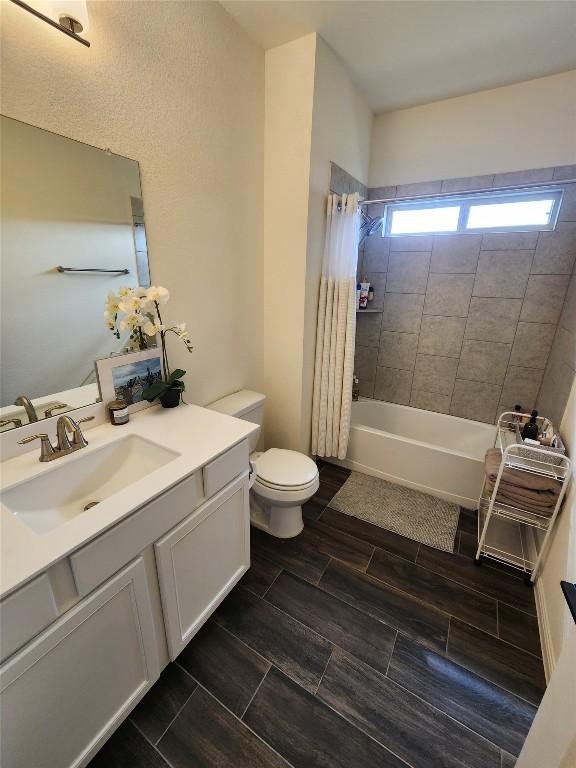 bathroom with toilet, wood tiled floor, shower / bath combo, and vanity