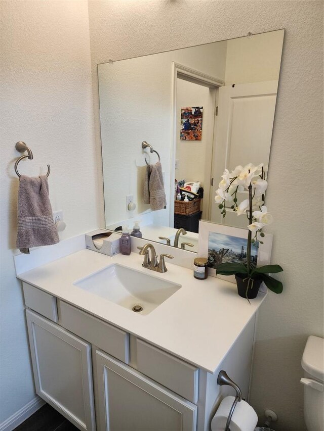 half bath featuring vanity and toilet