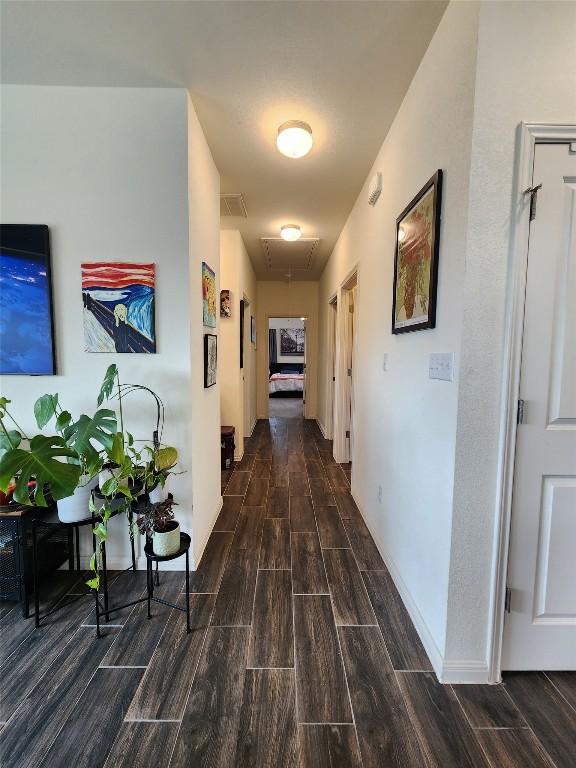hall with wood tiled floor, attic access, and visible vents