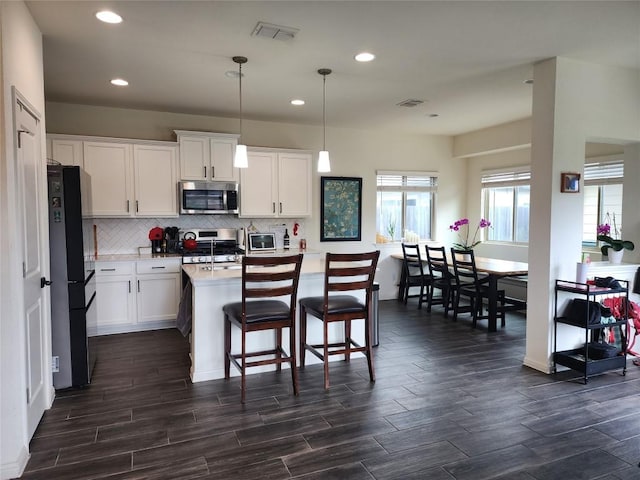 kitchen featuring light countertops, appliances with stainless steel finishes, dark wood finished floors, and visible vents