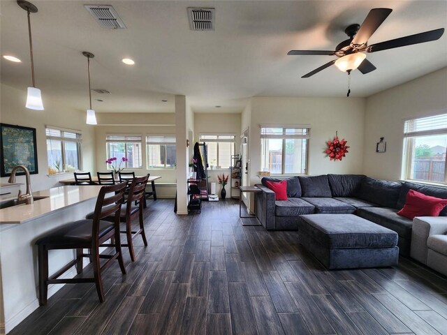 living area featuring a healthy amount of sunlight, dark wood-style flooring, and visible vents
