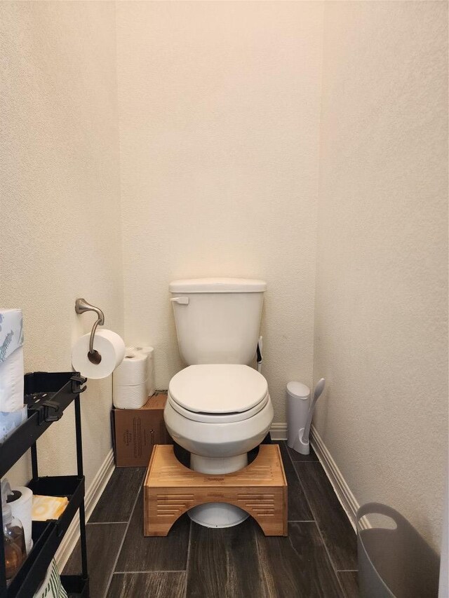 bathroom with toilet, baseboards, and wood finished floors