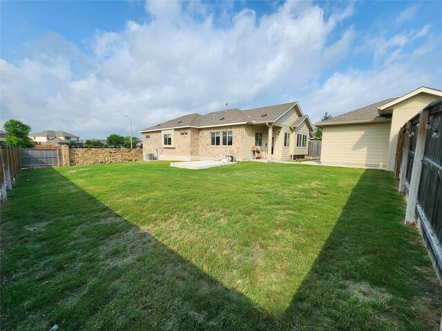 rear view of property featuring a lawn, a fenced backyard, a patio area, and brick siding