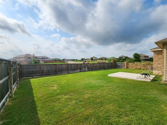 view of yard featuring a residential view, a fenced backyard, and a patio area