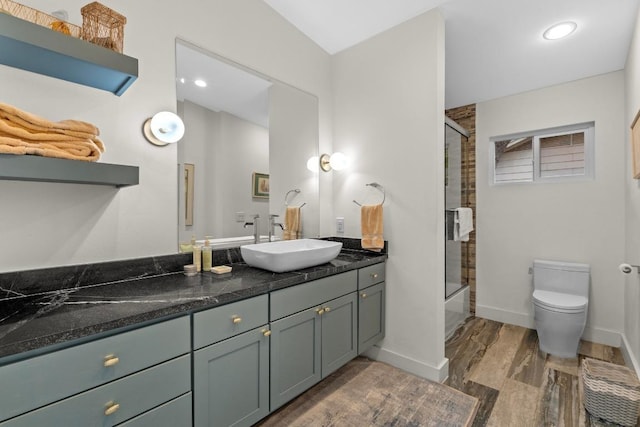 bathroom featuring vanity, toilet, enclosed tub / shower combo, recessed lighting, and wood finished floors