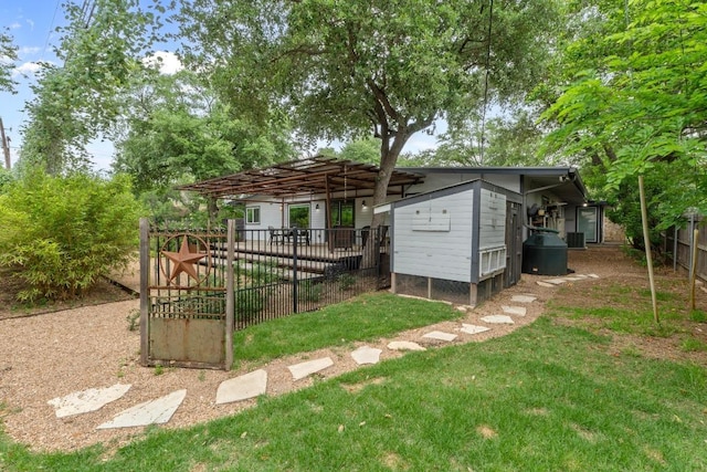 rear view of property featuring an outdoor structure, fence, and a yard