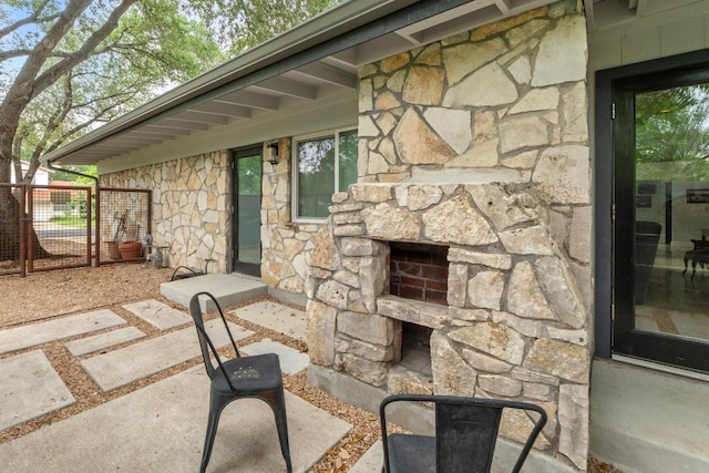 view of patio with fence, a fireplace, and a gate
