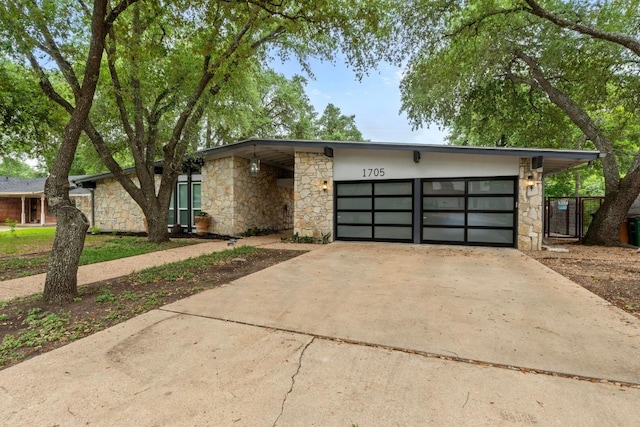 1705 Westmoor Dr, Austin, TX 78723 - view of front facade with stone siding, a garage, and driveway