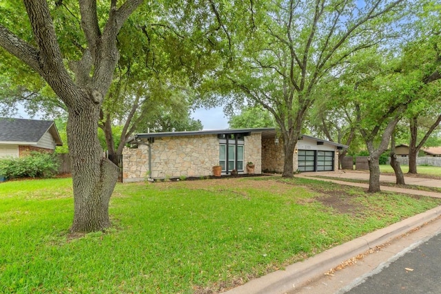 single story home featuring an attached garage, a front yard, driveway, and stone siding