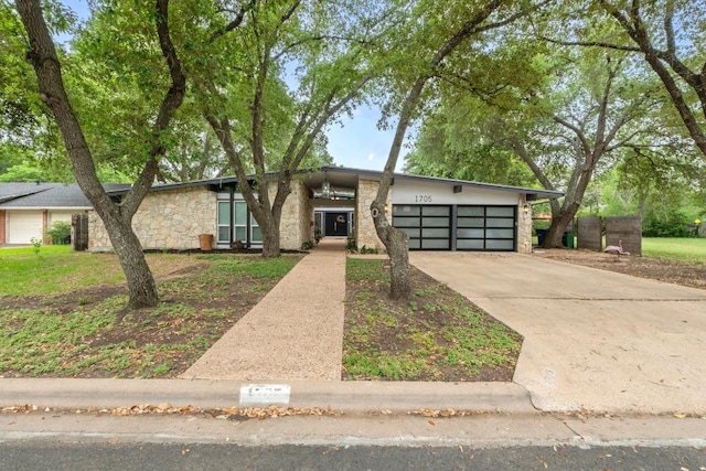 mid-century modern home with a garage, driveway, and stone siding
