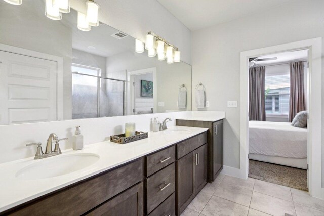 ensuite bathroom with double vanity, a sink, tile patterned floors, and a shower stall