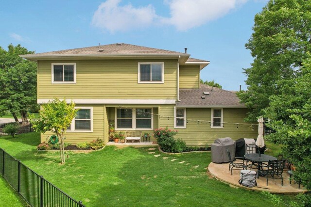 back of property with a fenced backyard, a shingled roof, a yard, and a patio area
