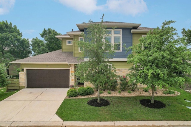prairie-style house with a garage, concrete driveway, a front lawn, and stone siding