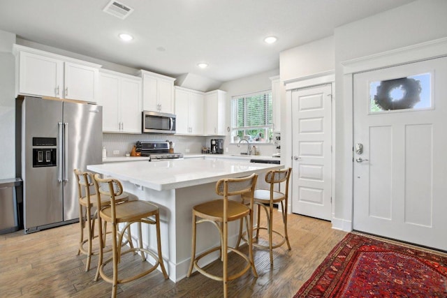 1708 Loyal Friend Dr Unit 46, Leander, TX 78641 - kitchen with stainless steel appliances, white cabinetry, a sink, a kitchen bar, and recessed lighting