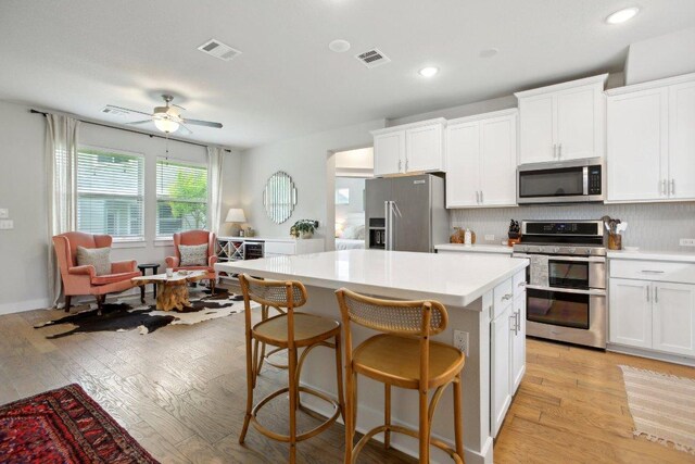 kitchen with light countertops, appliances with stainless steel finishes, a center island, and visible vents
