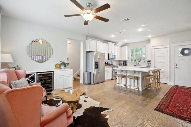 living area featuring ceiling fan, stairway, light wood finished floors, wine cooler, and recessed lighting
