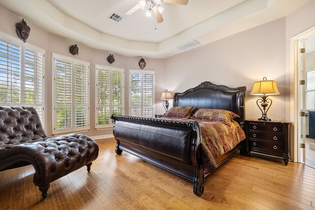 bedroom with visible vents, a raised ceiling, and wood finished floors
