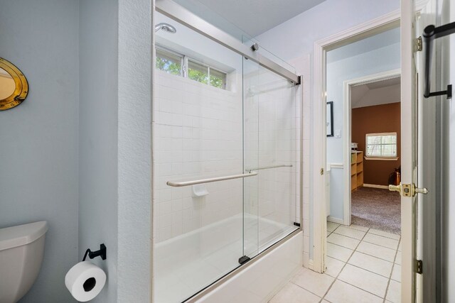 full bathroom featuring tile patterned floors, bath / shower combo with glass door, and toilet