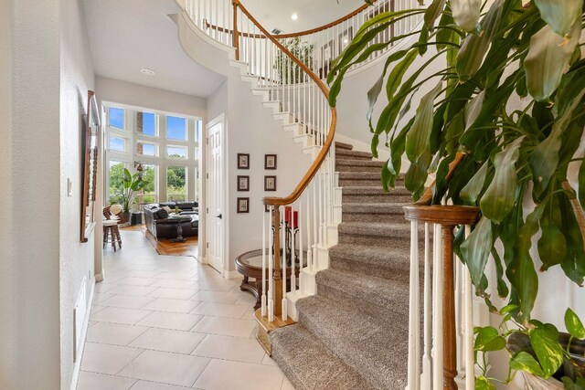 stairs with baseboards, tile patterned flooring, and a towering ceiling