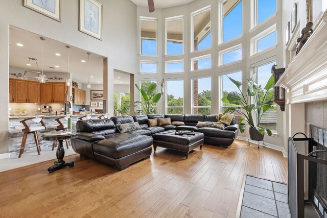 living area with a high ceiling, light wood-style floors, and a tile fireplace