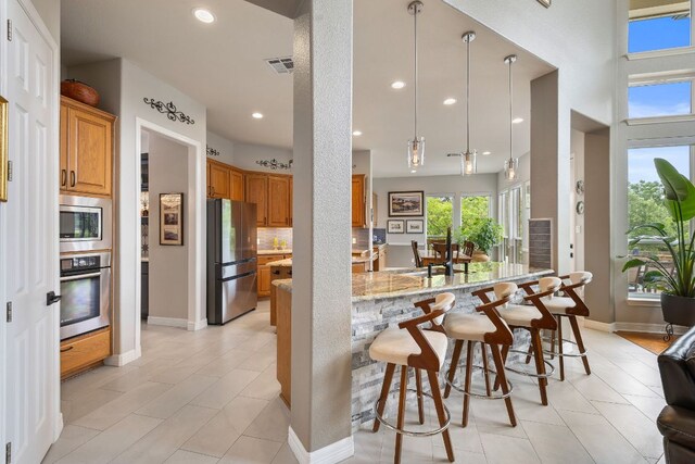 kitchen featuring visible vents, a breakfast bar area, a healthy amount of sunlight, and stainless steel appliances