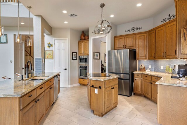 kitchen with appliances with stainless steel finishes, a sink, backsplash, visible vents, and a center island with sink