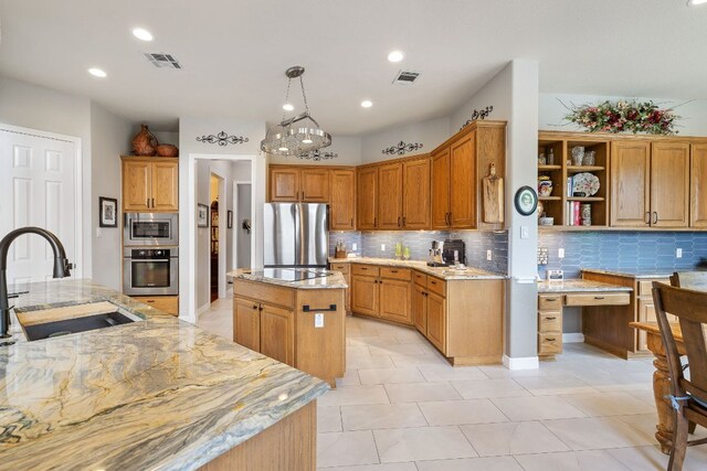 kitchen with appliances with stainless steel finishes, decorative backsplash, a sink, and a center island